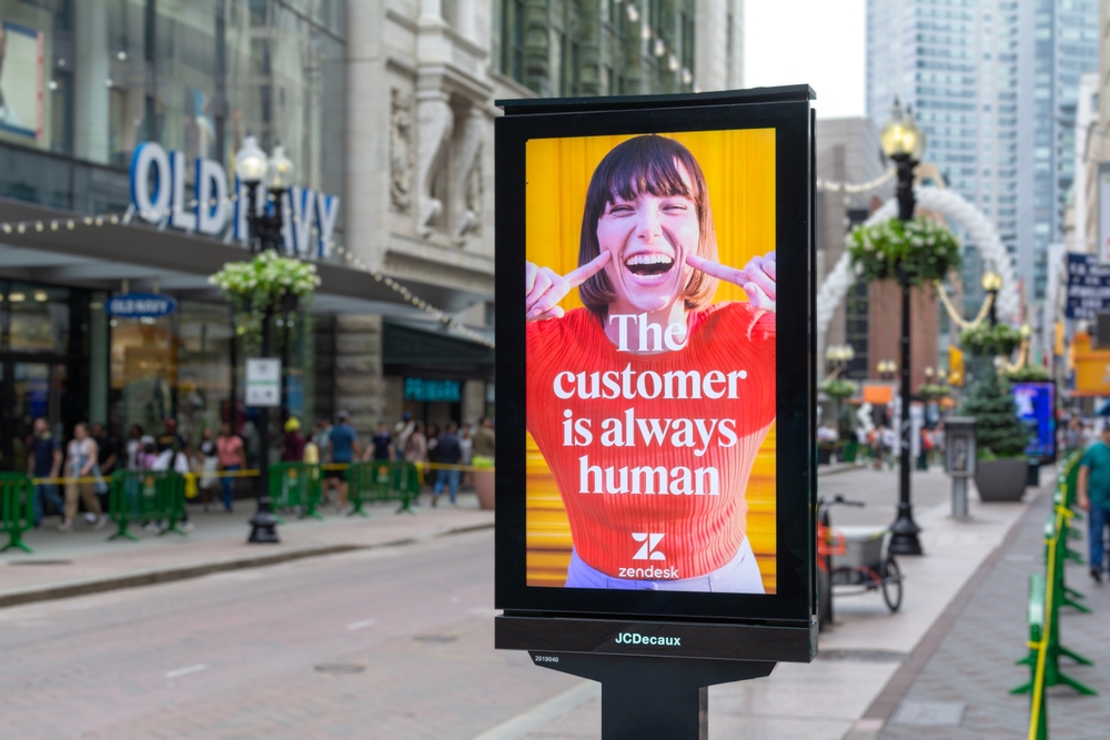 a sign with a line, 'the customer is always human' beside a street